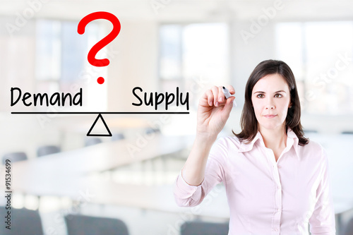 Fotografie Young business woman writing demand and supply compare on balance bar