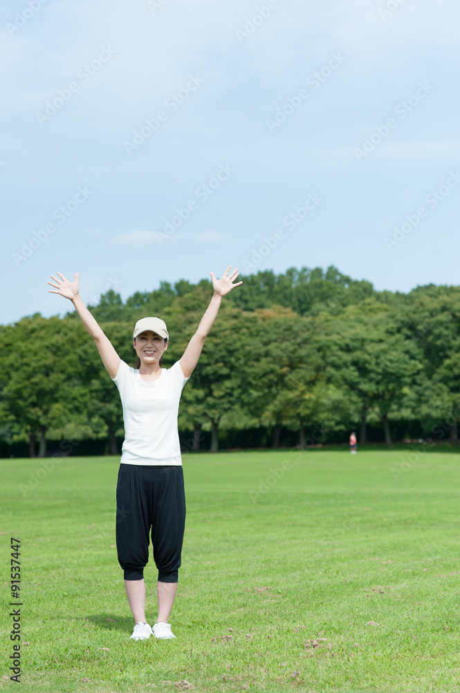 芝生の上で手を広げている女性