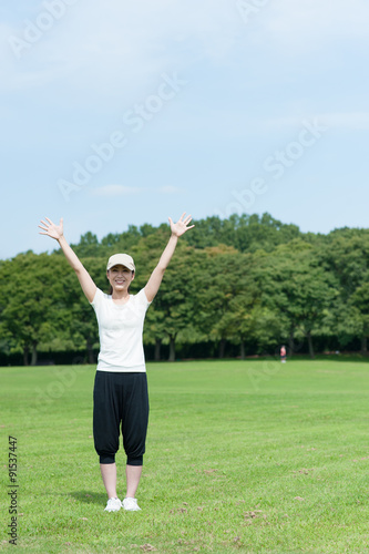 芝生の上で手を広げている女性