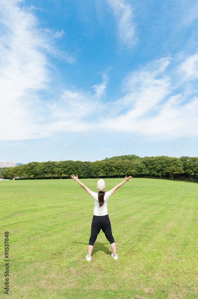 青空に向かって手を広げている女性の後ろ姿 青空に向かって手を広げている女性の後ろ姿
