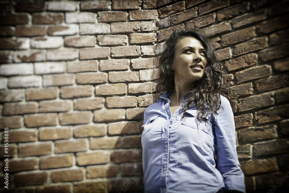Girl leaning against a brick wall