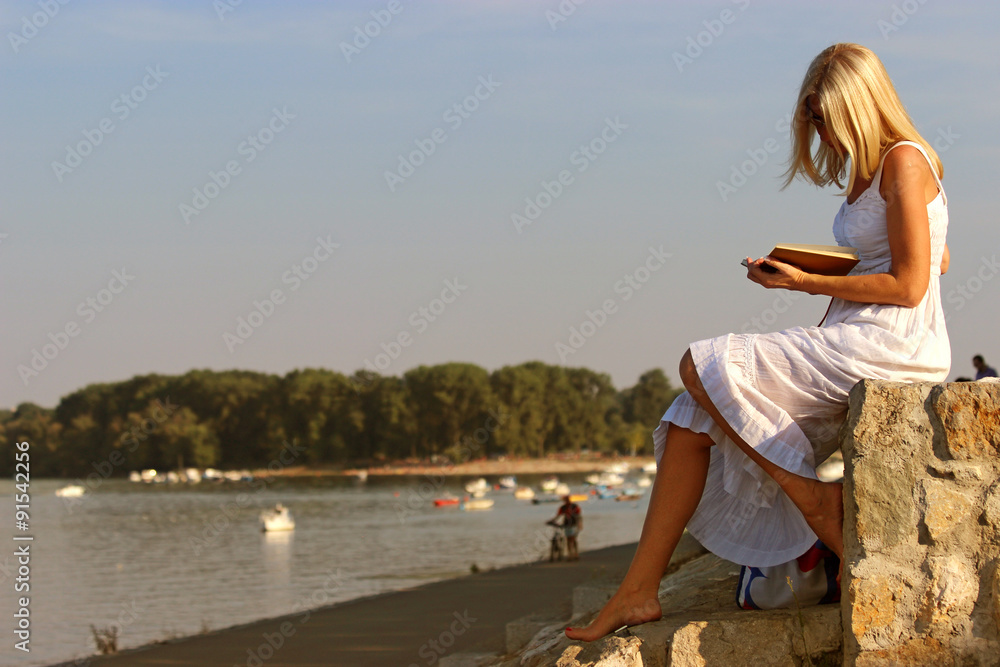 Woman reads a book on the river
