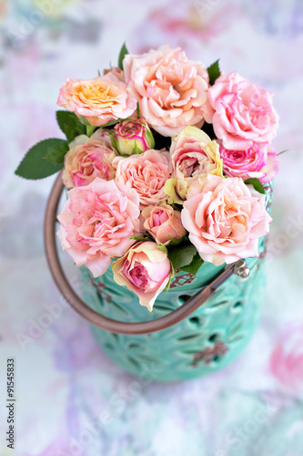 Delicate pink roses in a blue vase on the table.