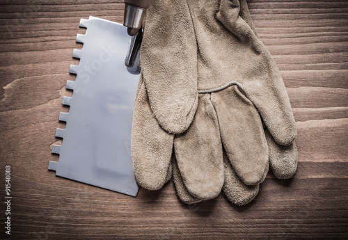 putty spattle and safety glove on wood board photo