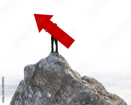 Man holding red arrow up sign on mountain peak