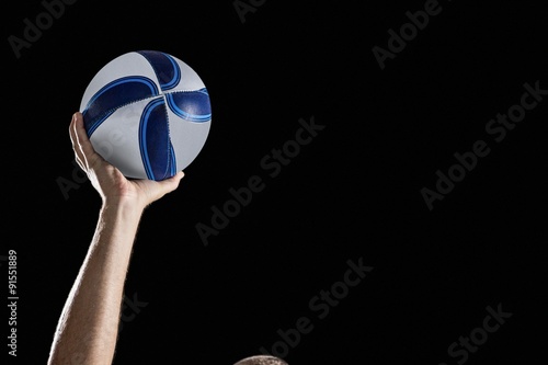 Rugby player with arm raised holding ball