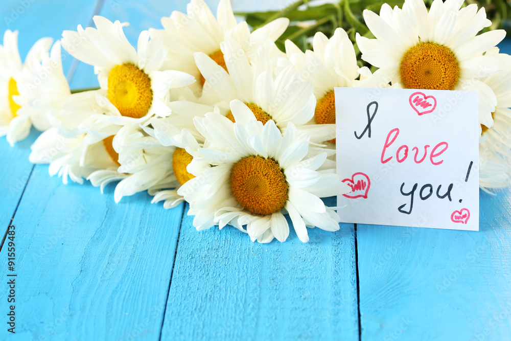 Obraz premium Chamomile flowers on a blue wooden background