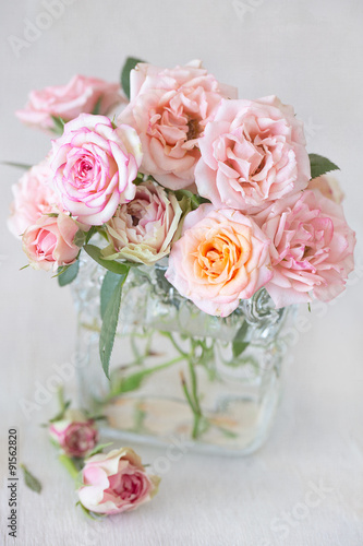 Beautiful fresh pink roses in a vase on a table .light background.