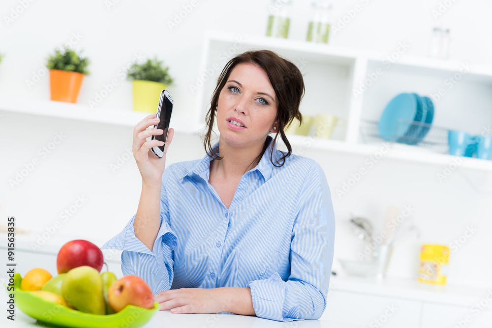 Junge Frau mit Mpbiltelefon in Küche