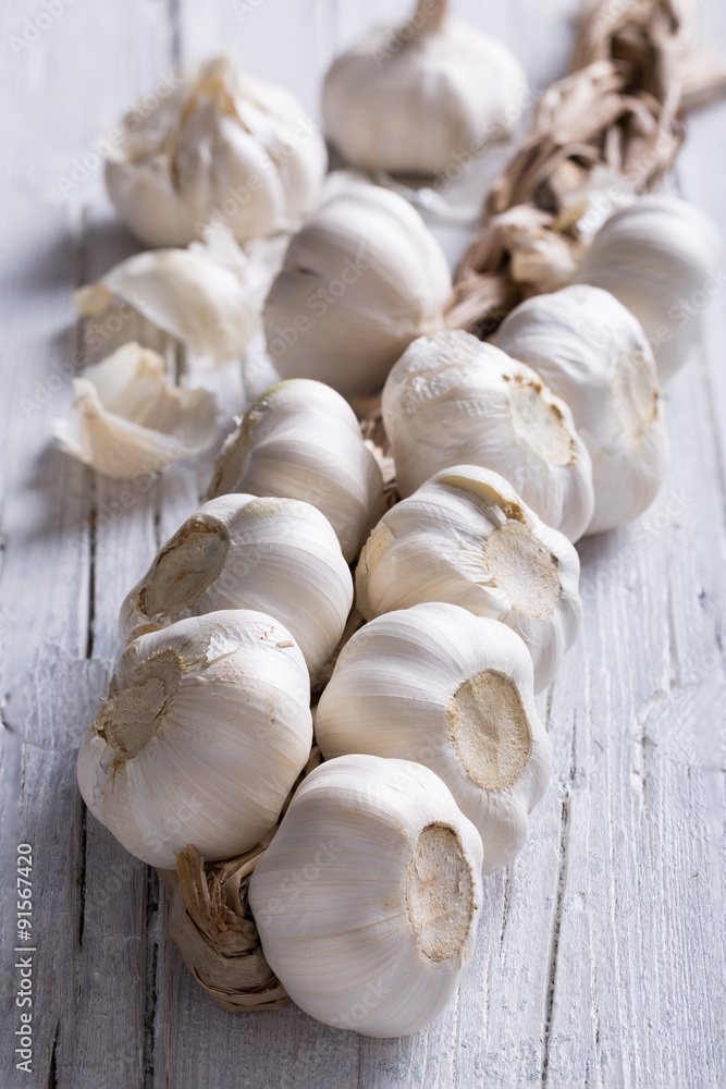 plait of white garlic on white wooden background plait of white garlic on white wooden background