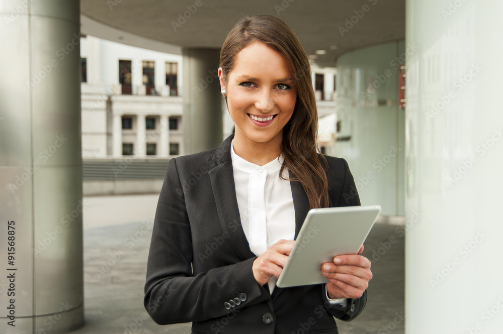 Young businesswoman touching tablet in the city. Smiling. Young businesswoman touching tablet in the city. Smiling.