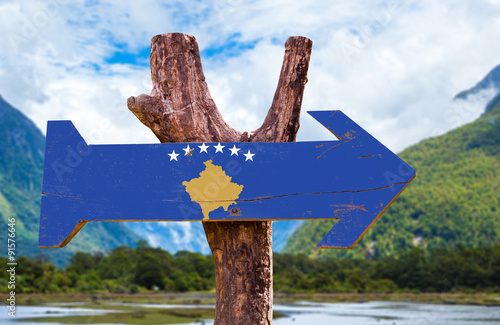 Kosovo Flag wooden sign with mountains on background photo