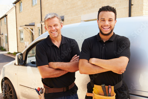 Portrait of a young and a middle aged tradesman by their van photo