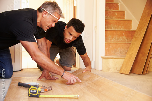 Photography Two men laying wood panel flooring in a house