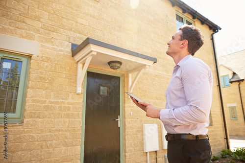 Male real estate agent looking up at a house exterior photo