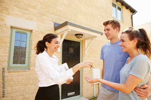 Foto Female real estate agent giving keys to new property owners