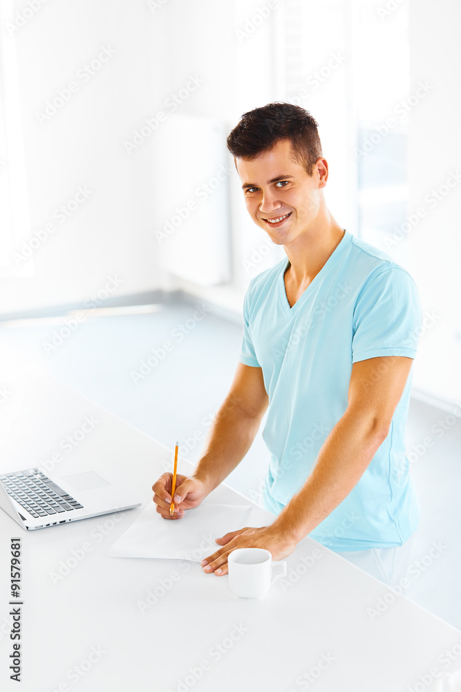 Man taking notes, smiling and looking at the camera Man taking notes, smiling and looking at the camera