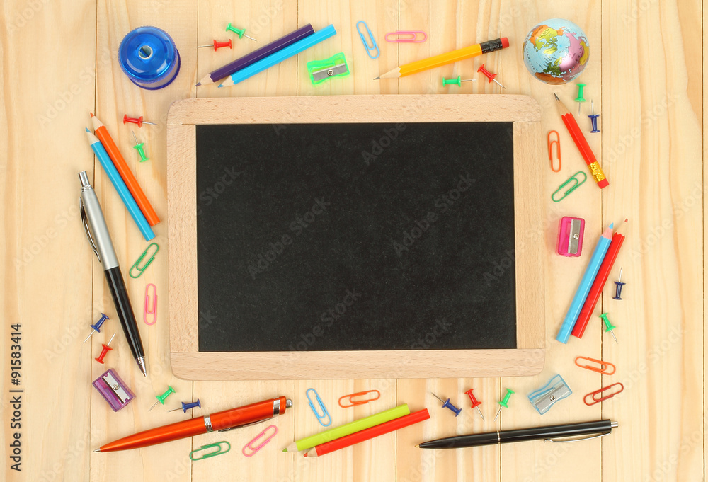 Chalkboard with school office supplies on wooden background Chalkboard with school office supplies on wooden background
