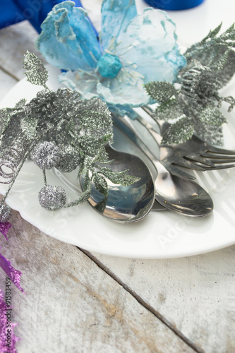 Christmas table setting in silver and blue tone on wooden table