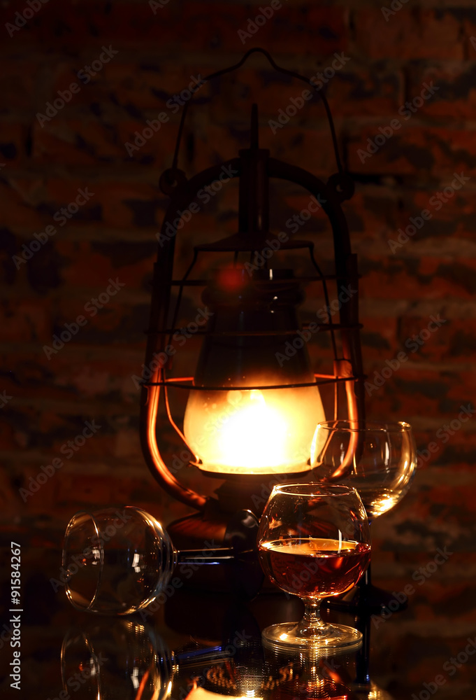 Cognac in a glass on a background of a burning lantern.. Cognac in a glass on a background of a burning lantern..