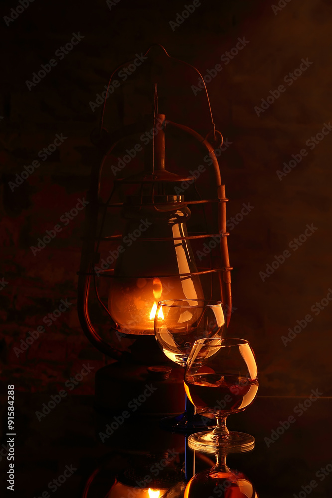 Cognac in glass and cigar on the background of a burning lantern..