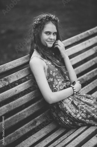Monochrome portrait of cute woman sitting on bench at park © Кирилл Рыжов