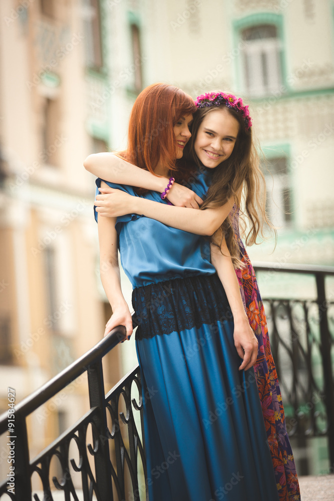 Portrait of smiling sisters hugging on street