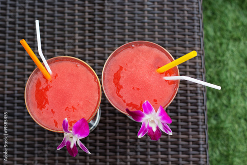 Two cocktails with strawberry and orchid flower