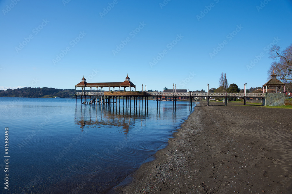 Wooden pier stretching out over the calm waters of Lake Llanquihue in the small town of Frutillar in southern Chile.