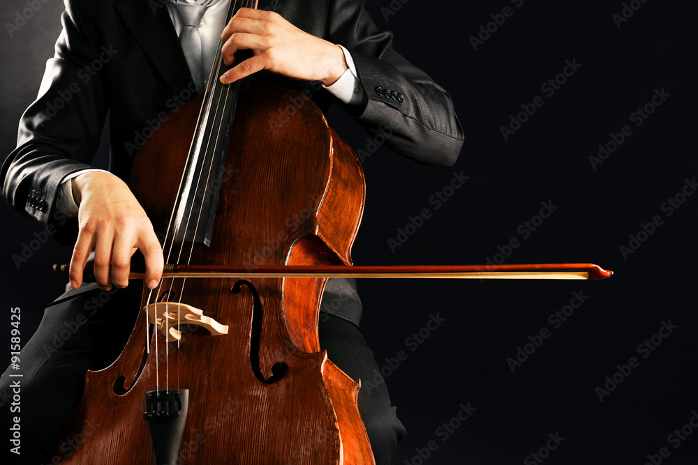 Obraz premium Man playing on cello on dark background