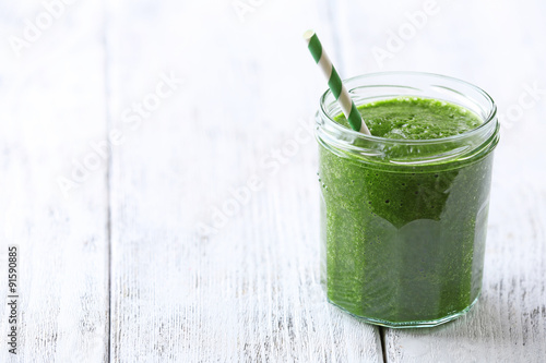 Glass of spinach juice on wooden background