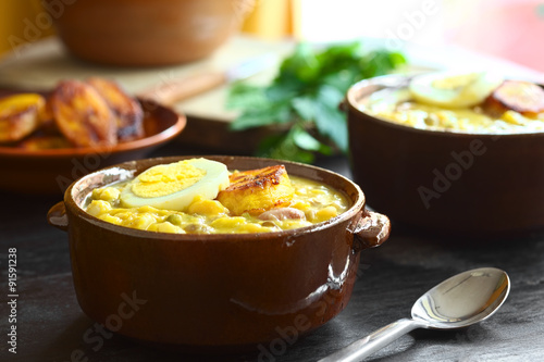 Ecuadorian soup Fanesca, traditionally eaten at Easter prepared from legumes, gourd, pumpkin, milk, salt cod (Selective Focus, Focus on the front of the egg and plantain on top of meal) photo