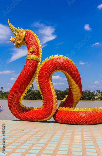 The Big Naga snake guarding Thai temple with white cloud and blue sky background