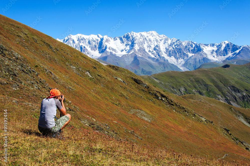 Hiker photographer taking picture of the valley with mountains 