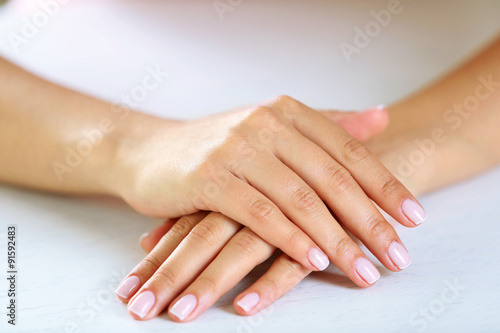 Woman hands with french manicure on table close-up