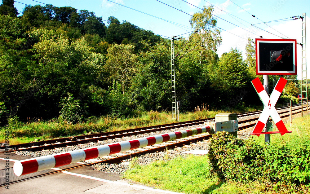 Naklejka premium Beschrankter Bahnübergang , Zug nähert sich in der Ferne