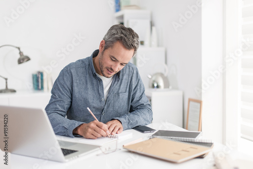 Portrait of a smiling grey hair man with beard, working at home