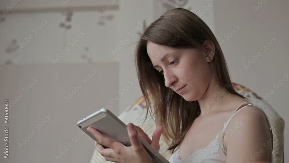 Woman at home relaxing in rocker, armchair and using tablet Woman at home relaxing in rocker, armchair and using tablet