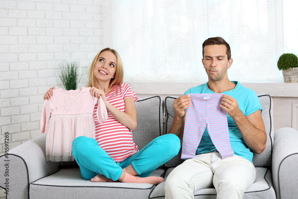 Obraz premium Young pregnant woman with husband on sofa in room