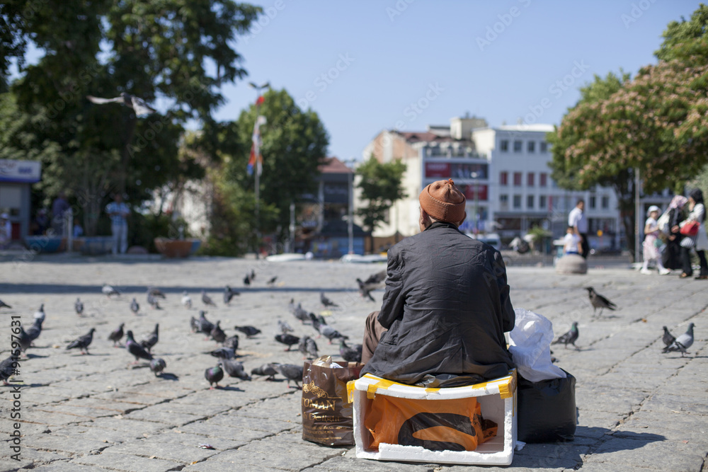 Hombre oriental sentado en plaza con palomas Hombre oriental sentado en plaza con palomas