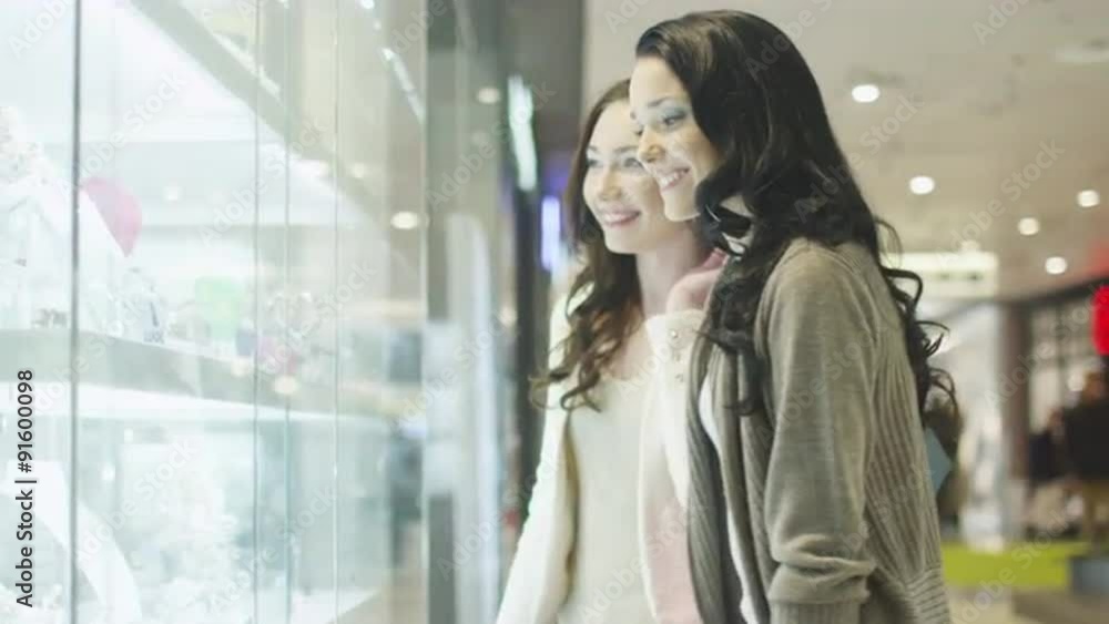 Two Girls are Looking at Display Window of Jewelry Store in Shopping Mall Two Girls are Looking at Display Window of Jewelry Store in Shopping Mall