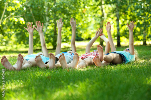 Happy active children lying on green grass in park