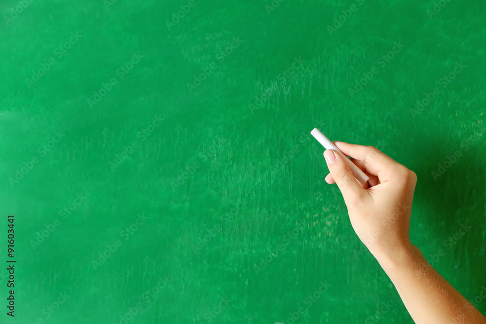 Naklejka premium Female hand writing on blackboard with chalk, close up