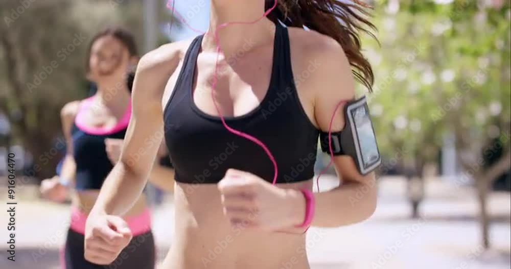 Close up crop of torso Two running women Fitness athletic friends jogging in the urban city Close up crop of torso Two running women Fitness athletic friends jogging in the urban city