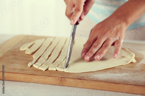 Woman making apple pie on wooden table, on light background