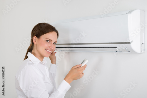 Businesswoman Operating Air Conditioner