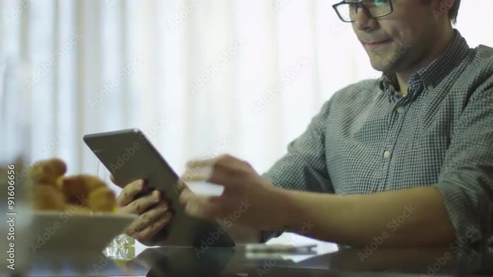 Man is Using Tablet at Home during Breakfast Man is Using Tablet at Home during Breakfast