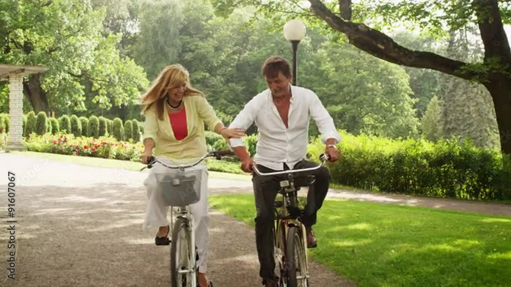 Happy Adult Couple Riding Bicycles in Park. Happy Adult Couple Riding Bicycles in Park.