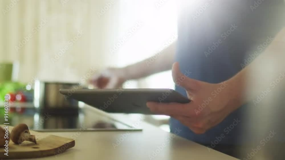 Man is Using Tablet PC while Preparing Food Man is Using Tablet PC while Preparing Food