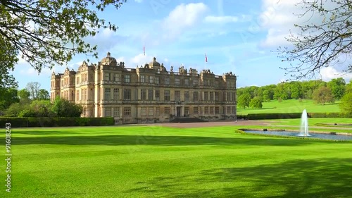Establishing shot of the Longleat mansion in England amidst green lawns and fountains. photo